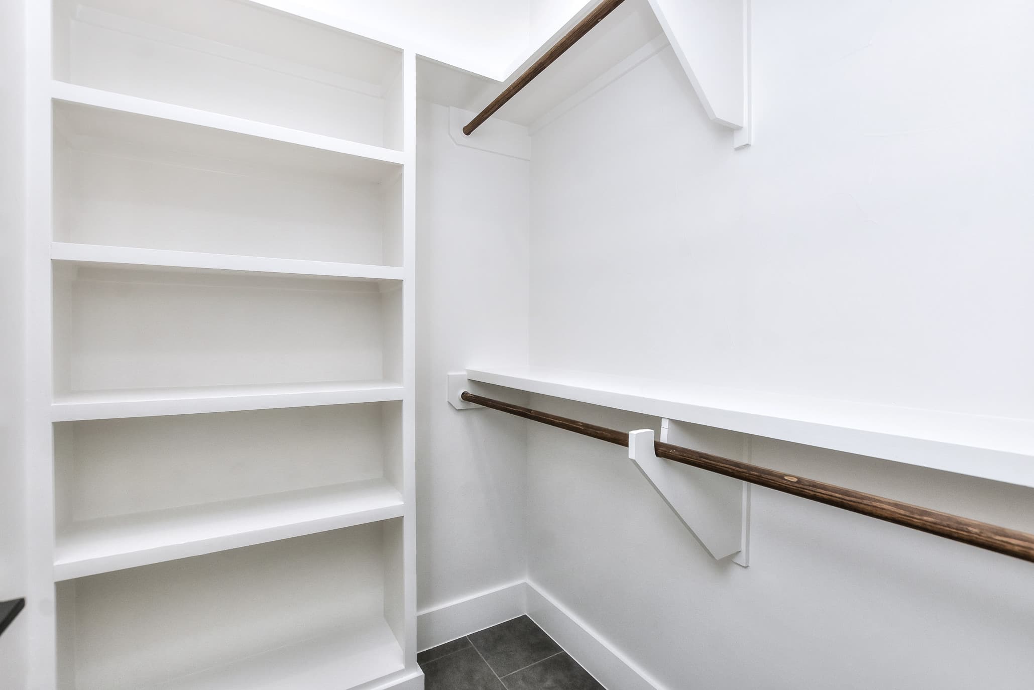 Walk-in closet with white built-in shelves and a wood hanging rod