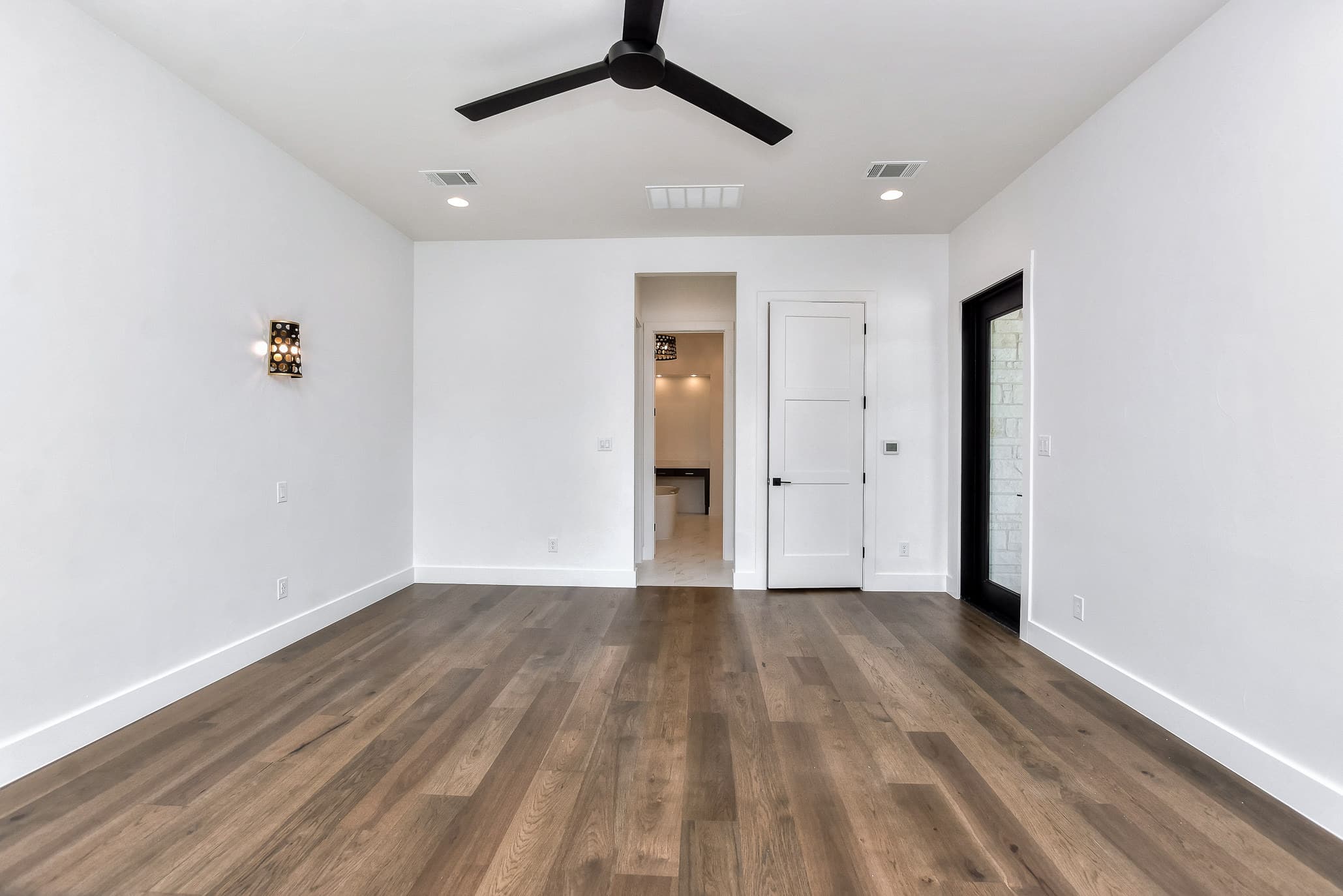 Primary bedroom with a ceiling fan and a view through to the bath and closet