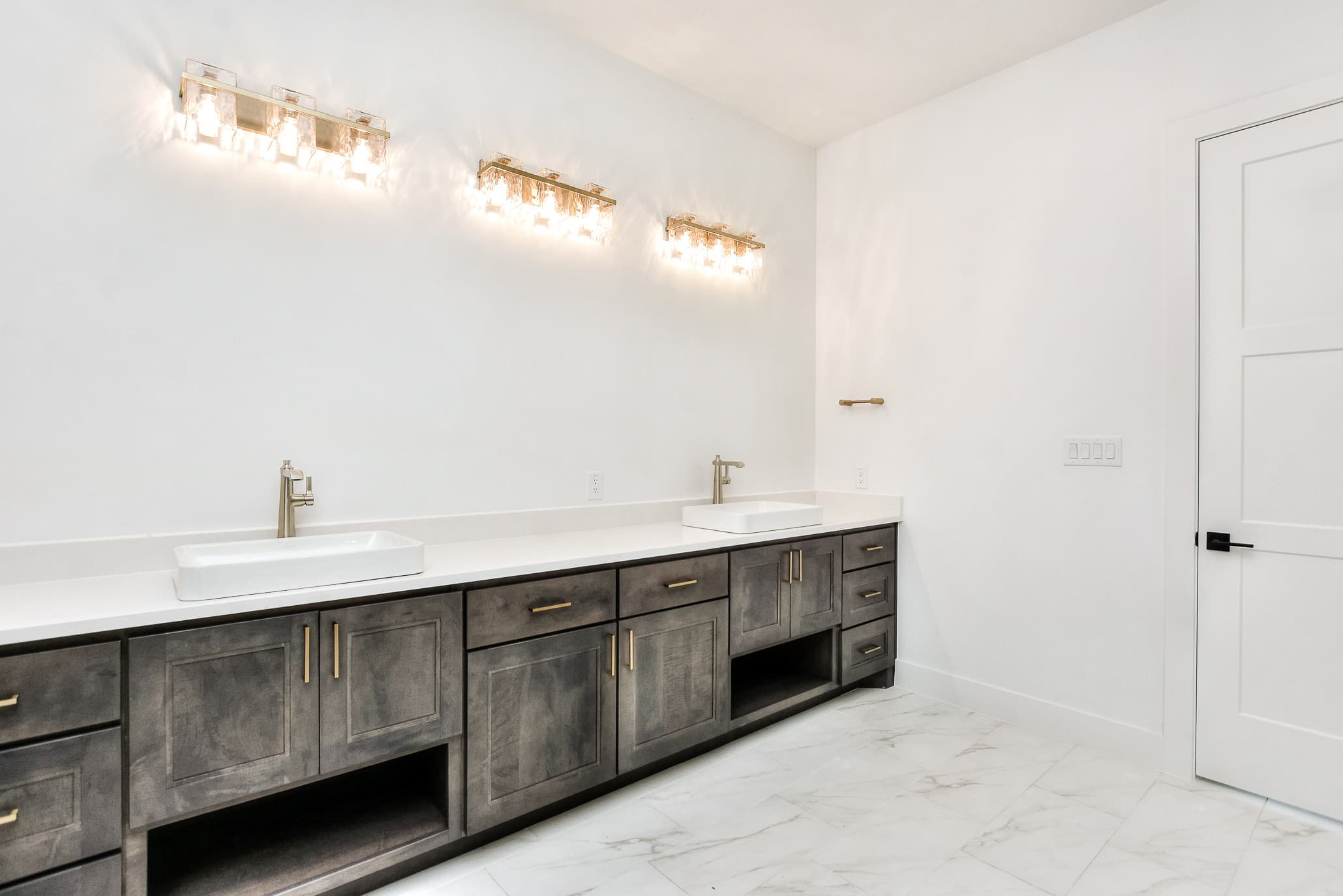 Long double vanity in gray wood with vessel sinks, brass pulls and brass vanity lights