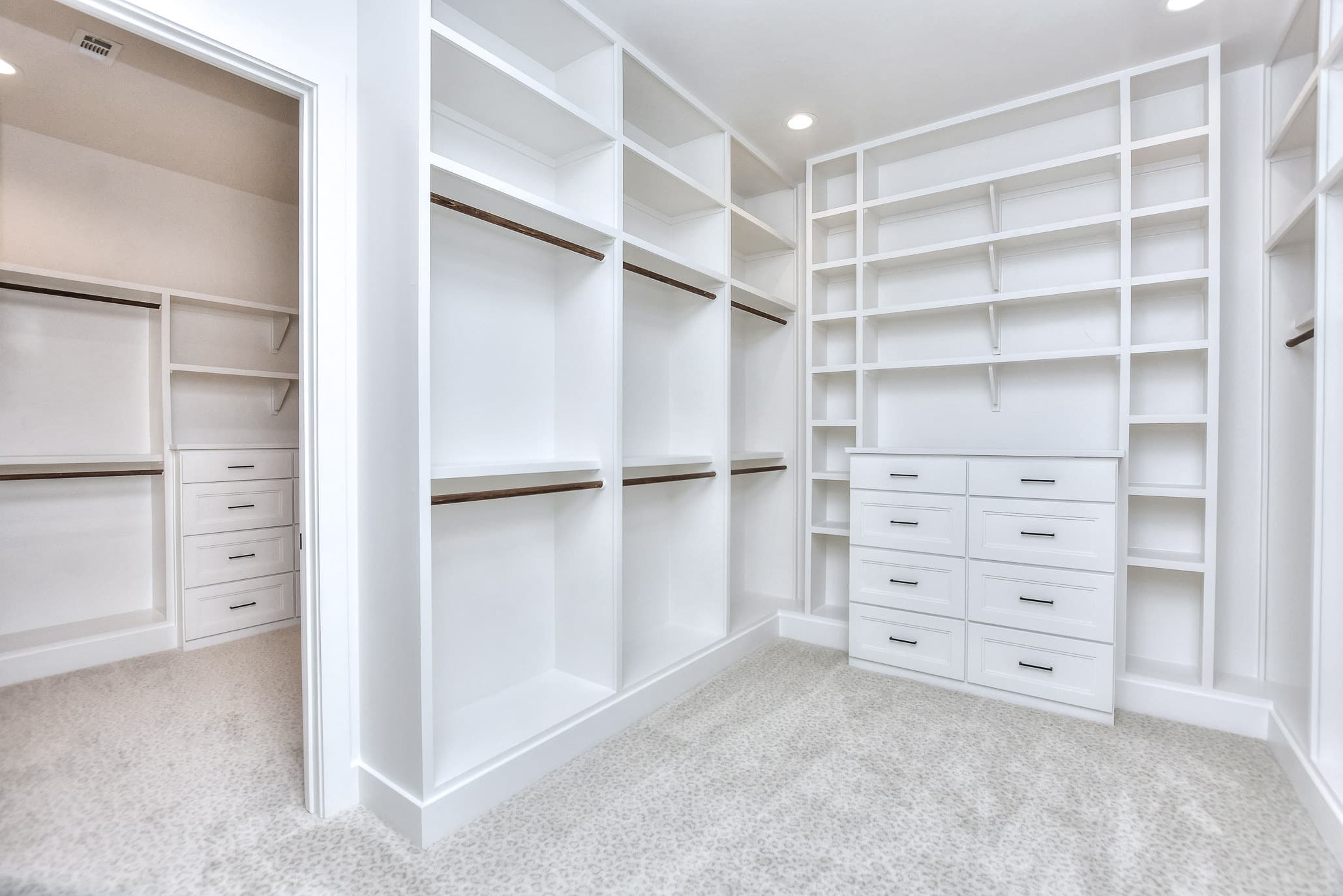 Walk-in closet with white built-in shelving, drawers and hanging rods