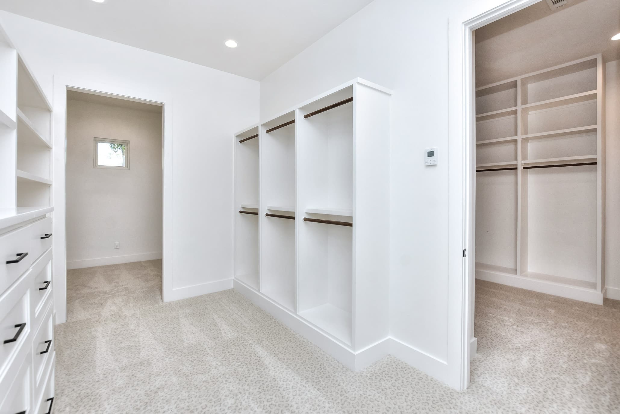 Spacious walk-in closet with built-in cabinets, drawers and an adjoining closet room