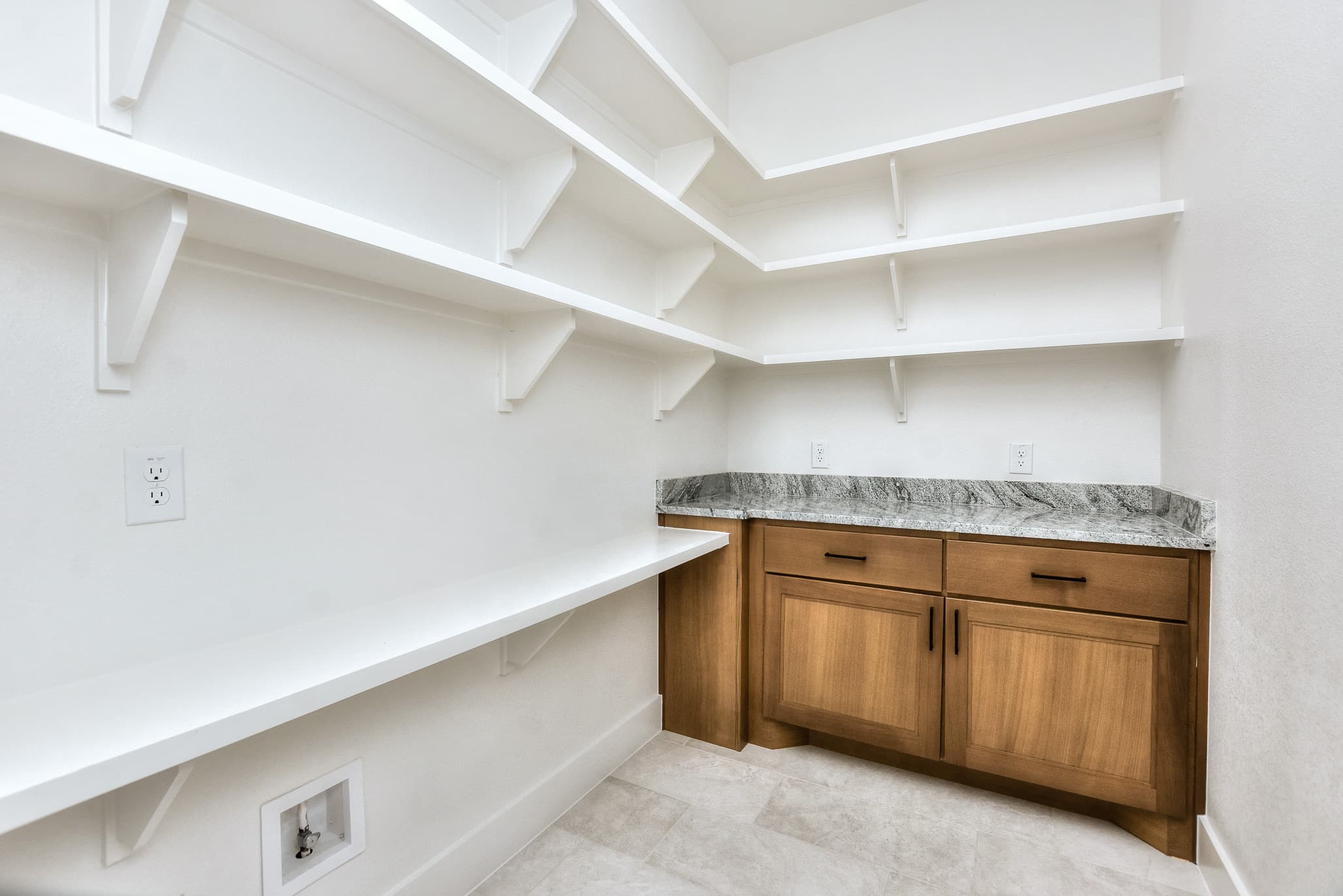 Walk-in pantry with white shelving and a built-in granite-topped wood cabinet