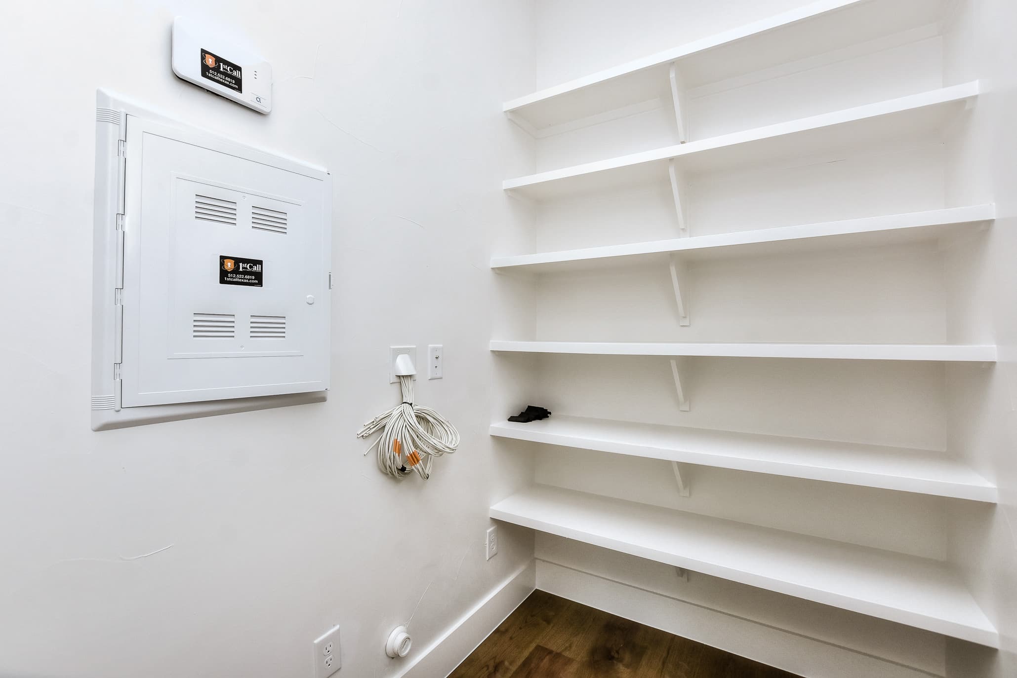 Utility space with white wall shelving next to the electrical panel