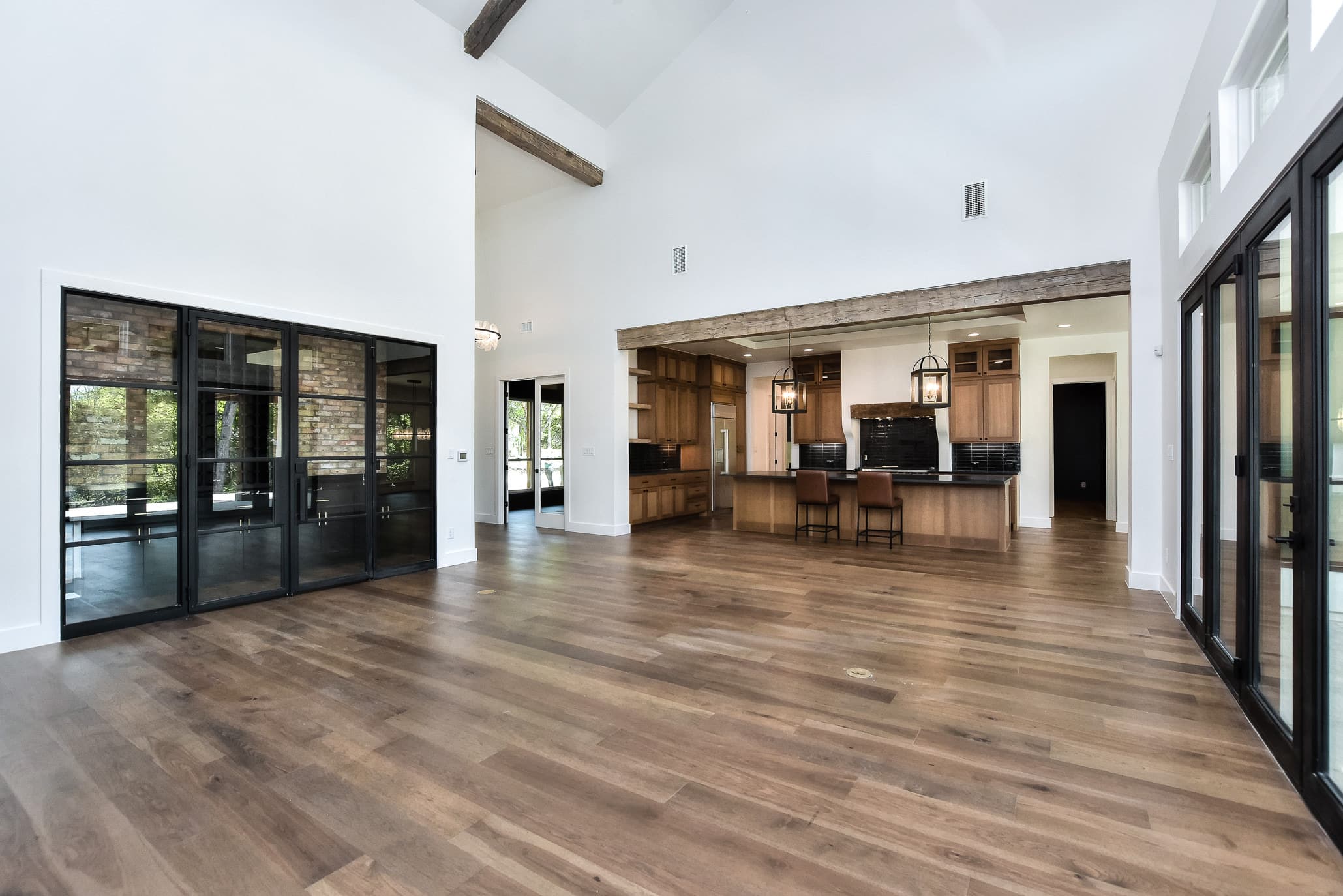 Great room with a vaulted ceiling, steel-framed glass doors and exposed beams, open to the kitchen