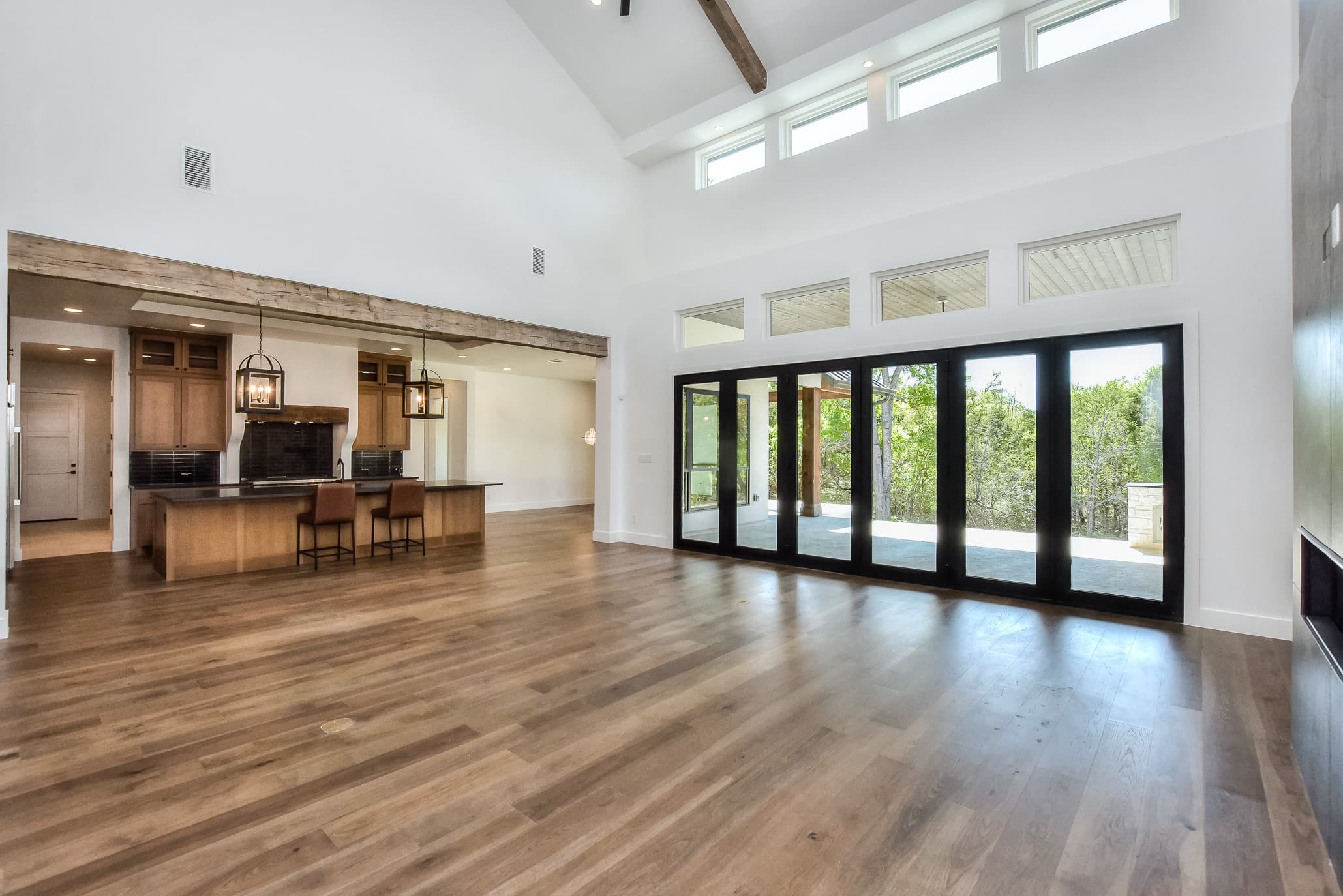 Open great room with a vaulted ceiling, clerestory windows and steel folding glass doors to the patio