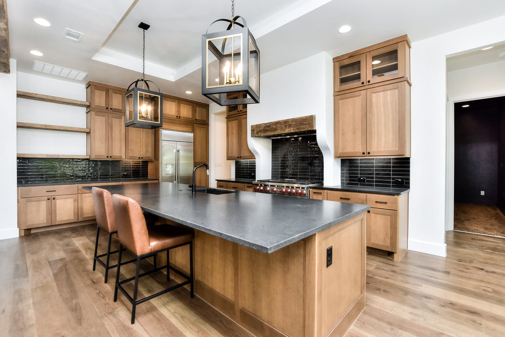 Kitchen with a large island, lantern pendants, a stucco range hood and natural wood cabinets