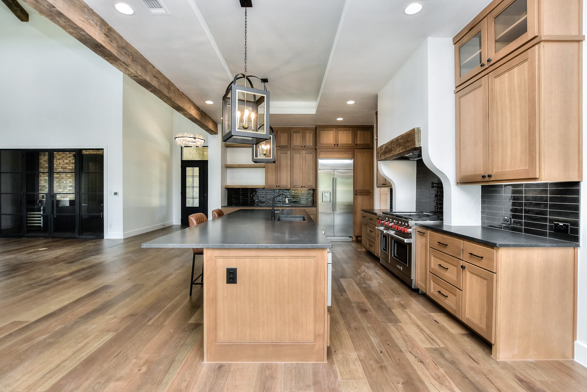 Long kitchen with oak cabinetry, a reclaimed-wood beam, island and professional range