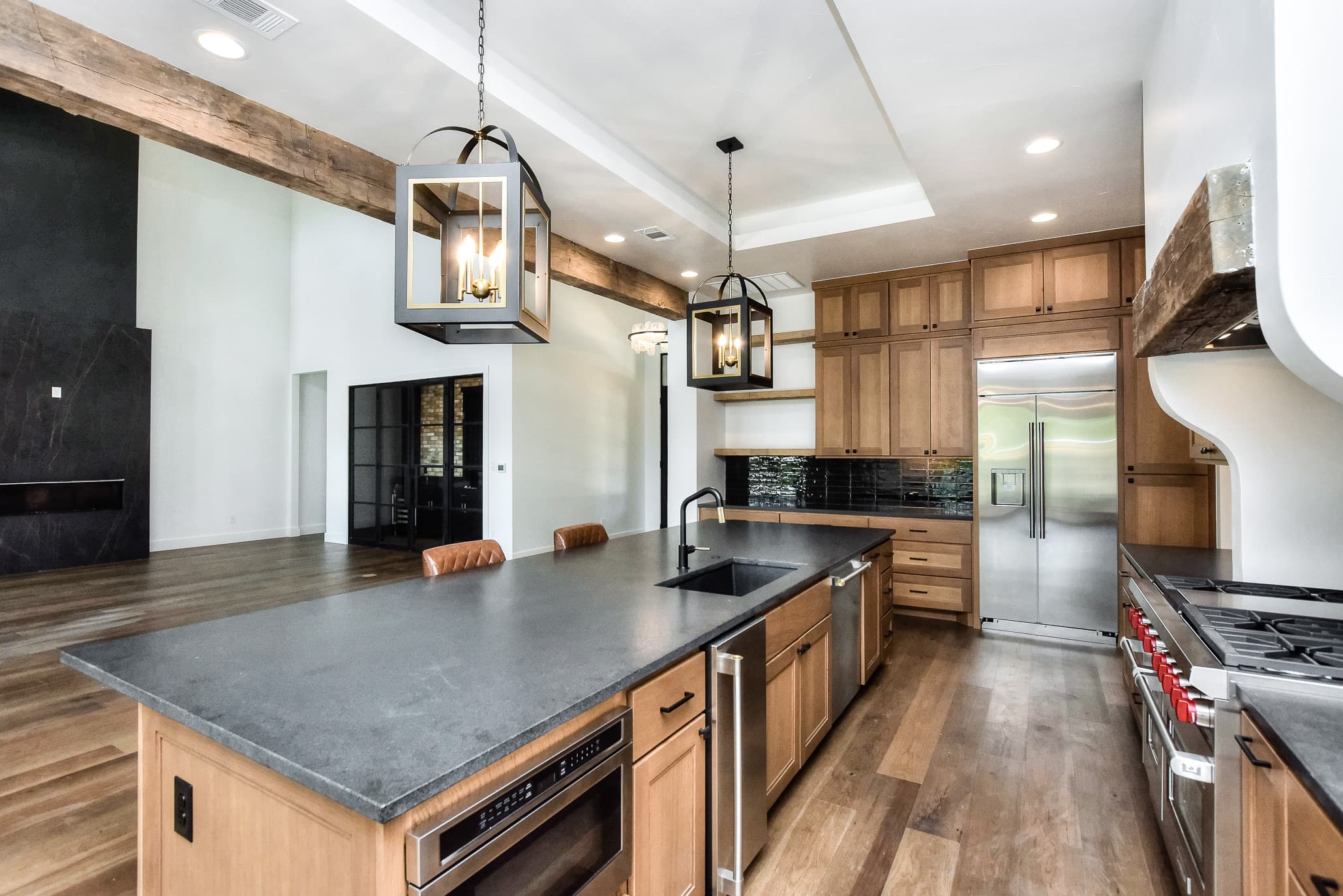 Kitchen island with a dark counter, built-in microwave drawer and view to a black fireplace in the great room