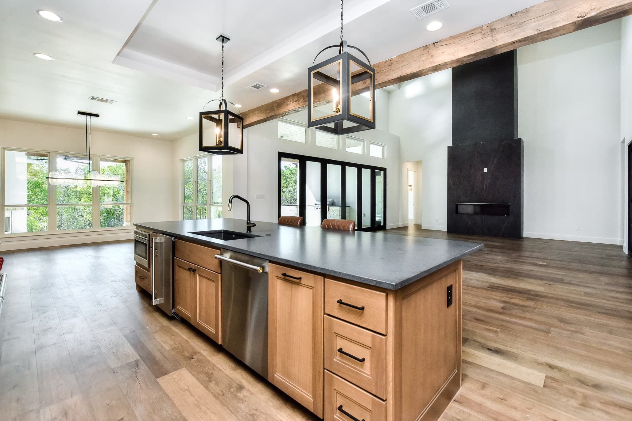 Kitchen island with a sink and drawers opening to the dining area and a dark fireplace