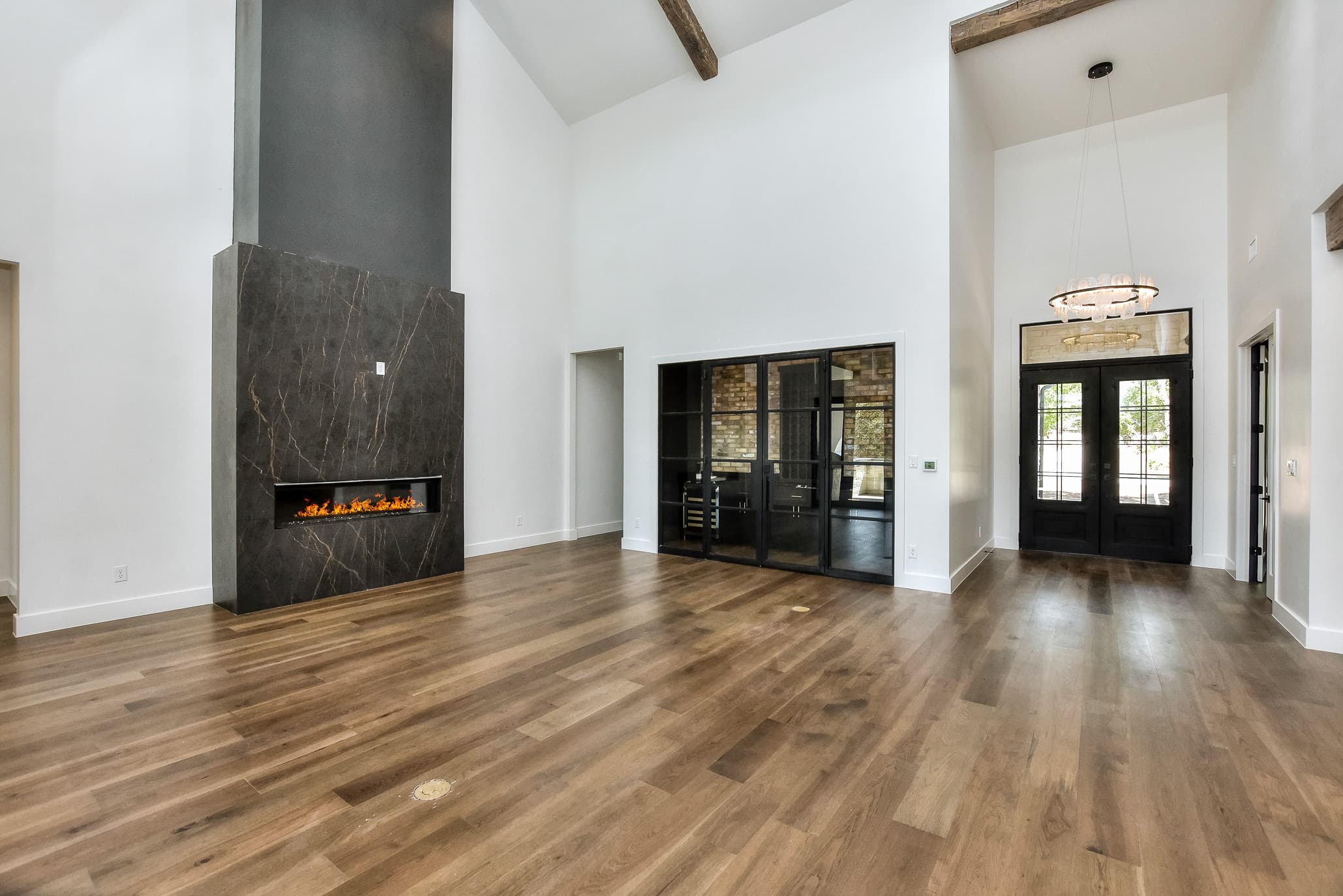 Great room looking toward the front entry, with a linear fireplace in a dark stone surround