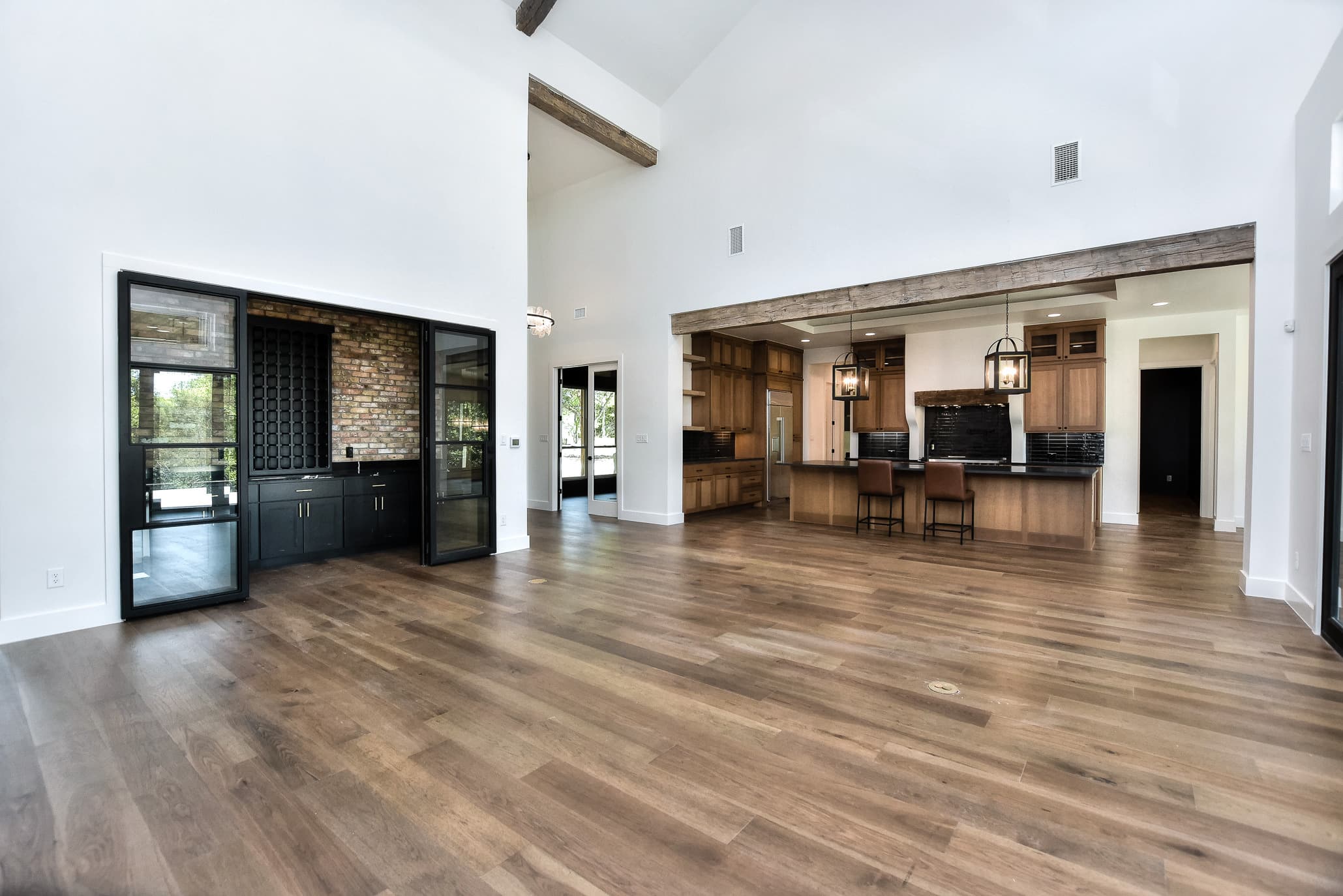 Great room with a vaulted ceiling and exposed beams opening to the kitchen and wine bar