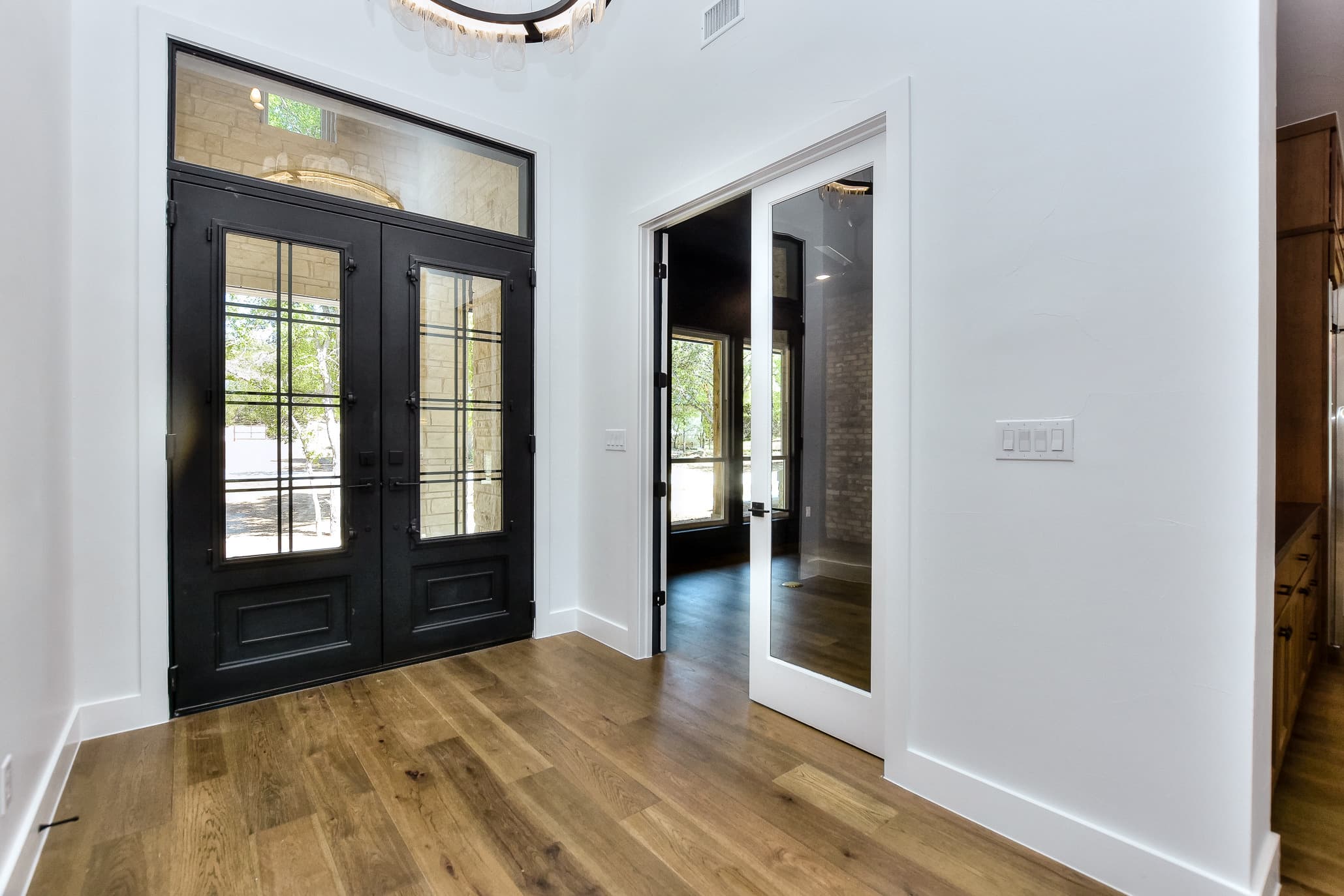 Entry hall with iron double doors, a glass-paned pocket door and oak floors