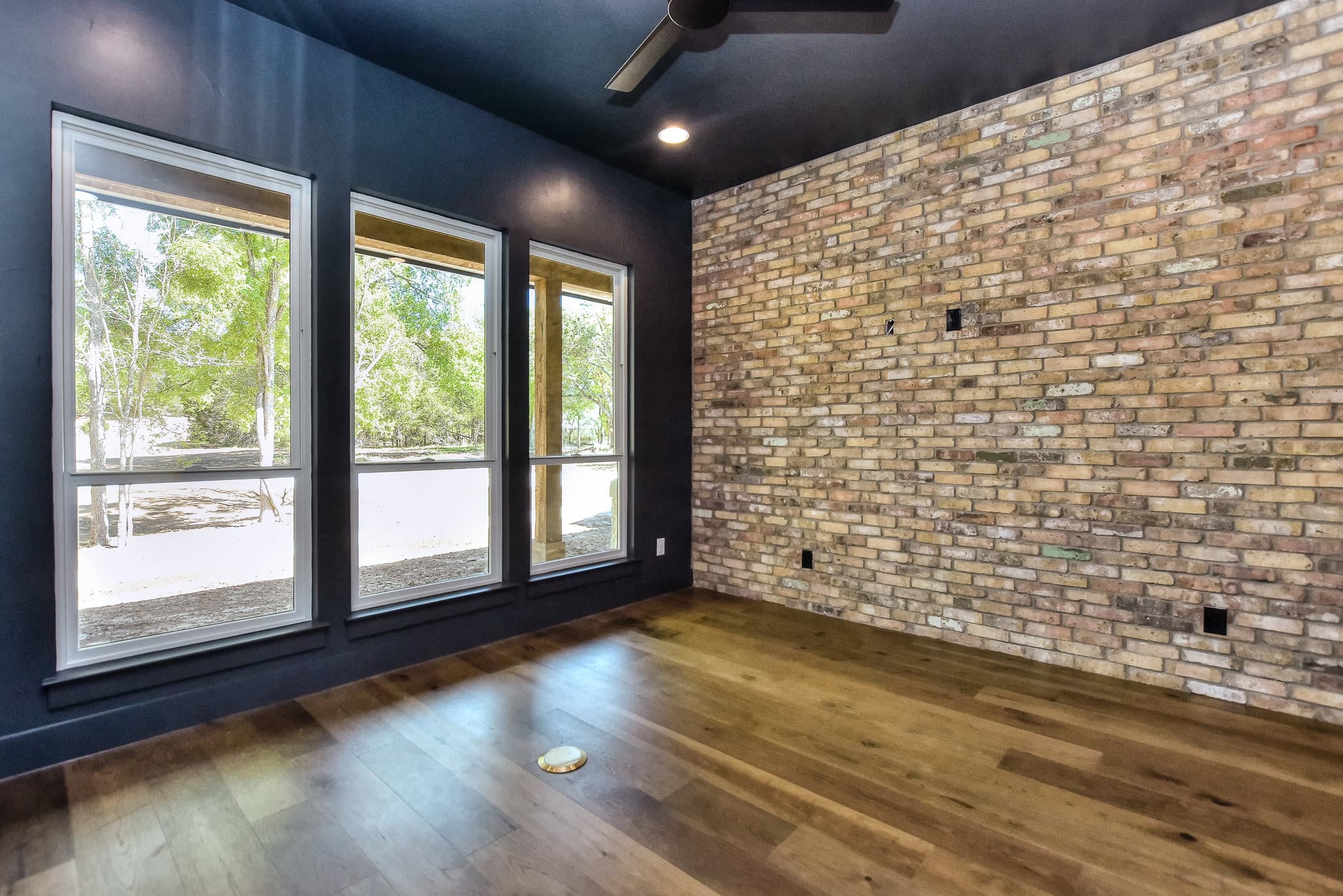 Study with a navy ceiling, exposed brick wall and large windows