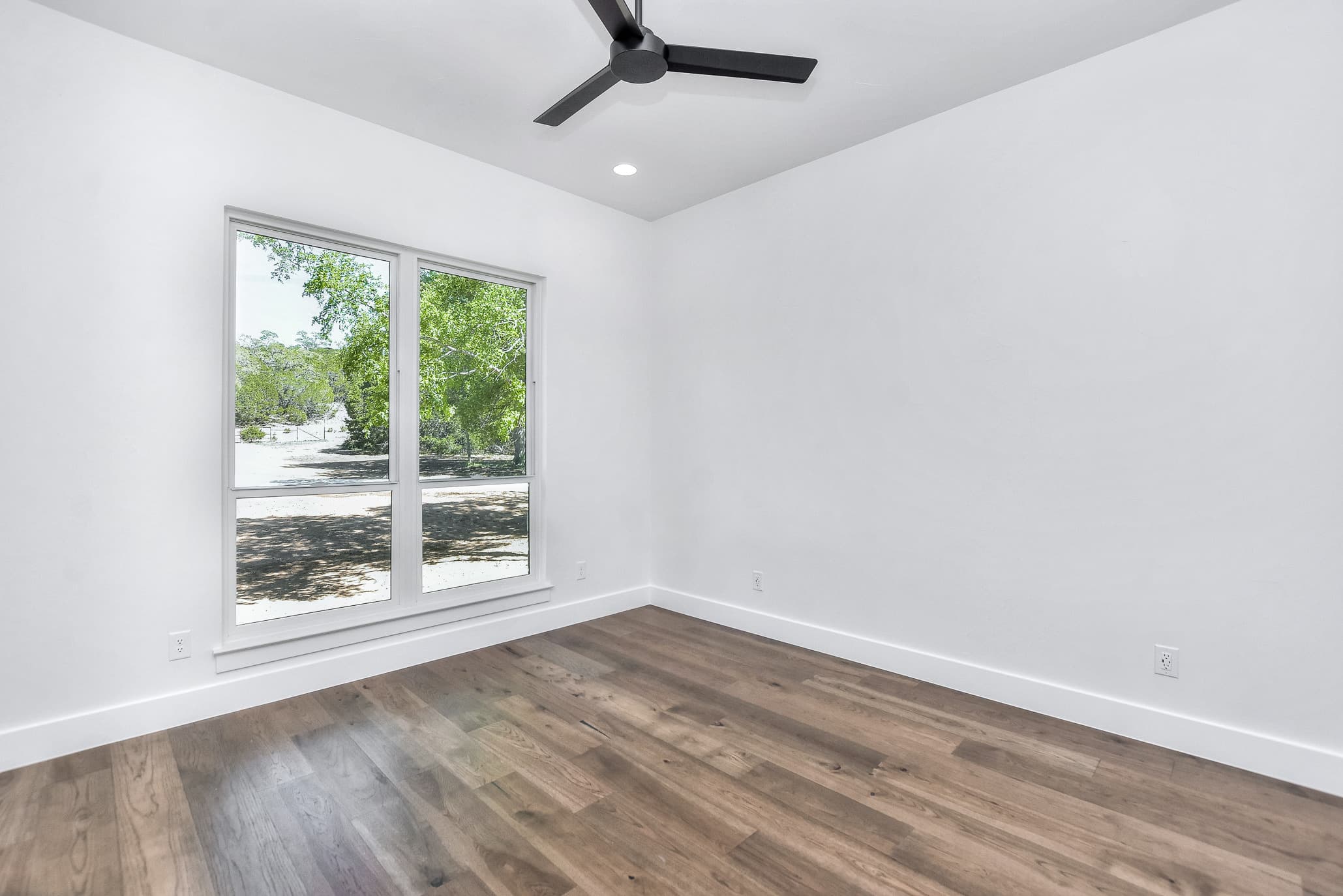 Bedroom with a black ceiling fan, white walls and a pair of windows