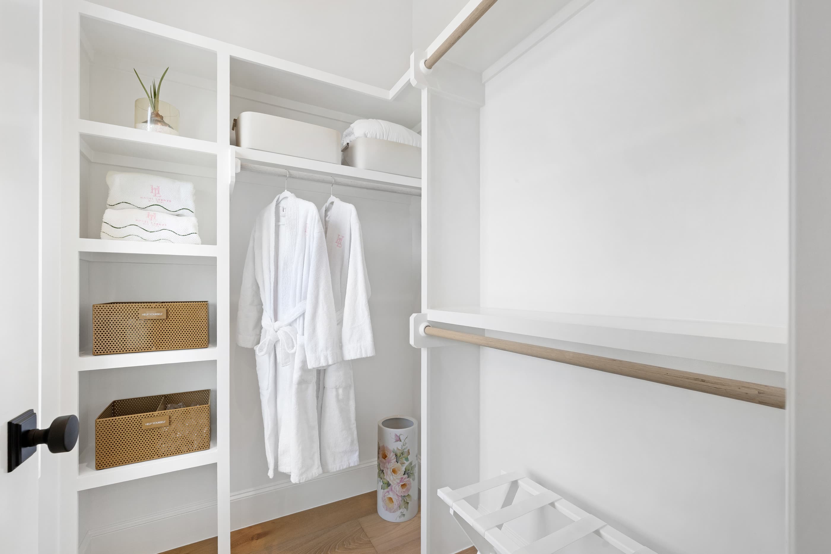 Walk-in closet with white built-in shelving, woven baskets and hanging robes