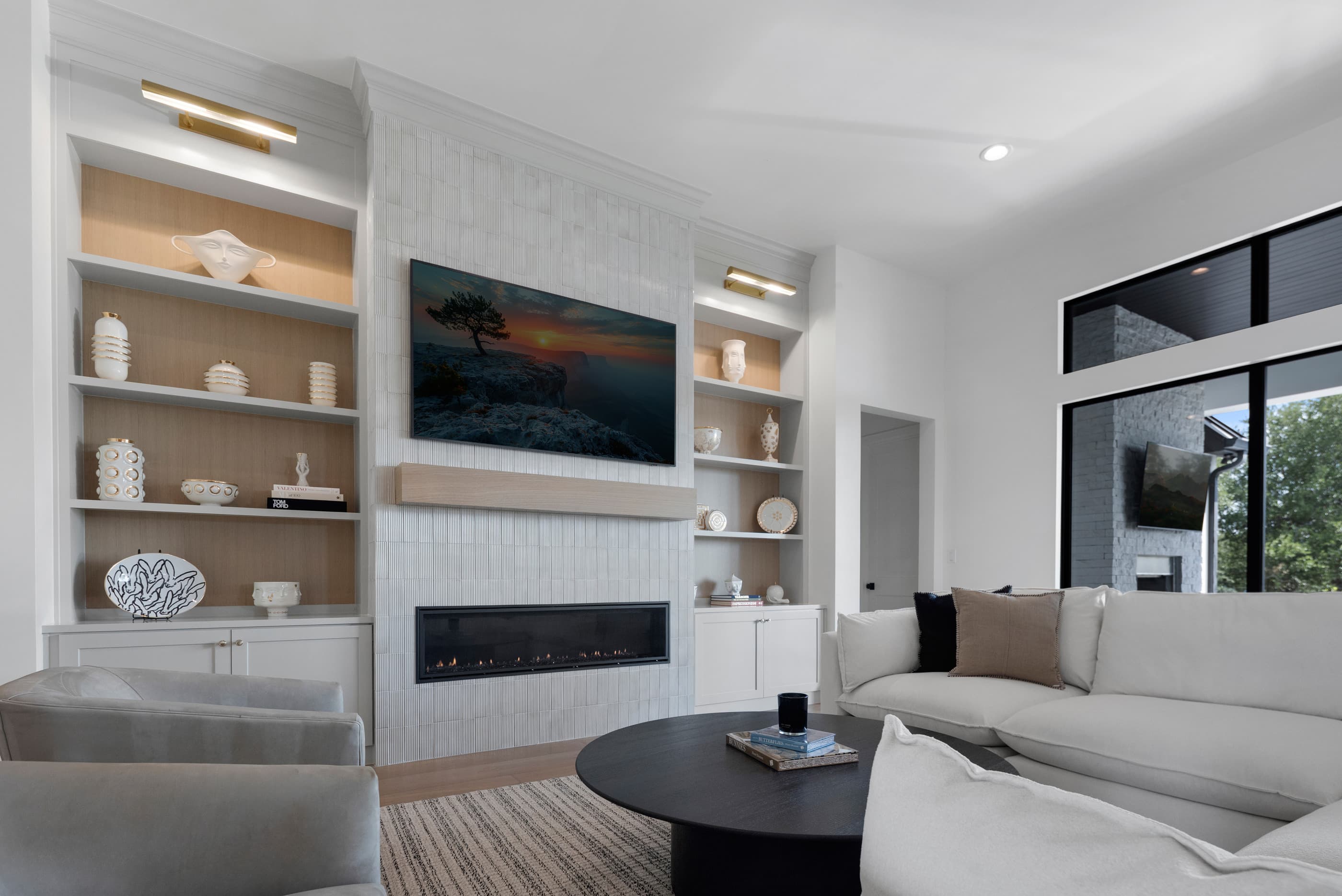 Living room with a linear gas fireplace, white built-in shelving with oak backing and a wall-mounted TV