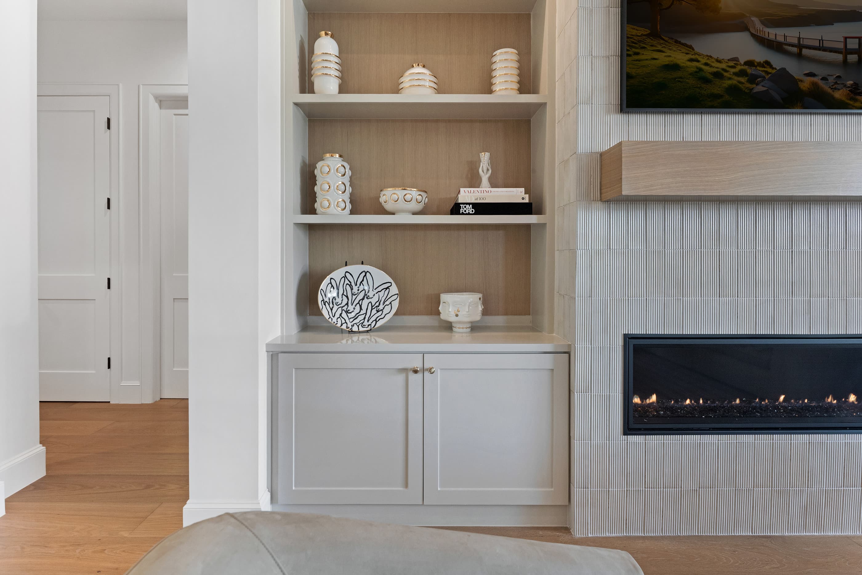 Built-in cabinetry and open shelving beside a modern linear fireplace clad in vertical tile