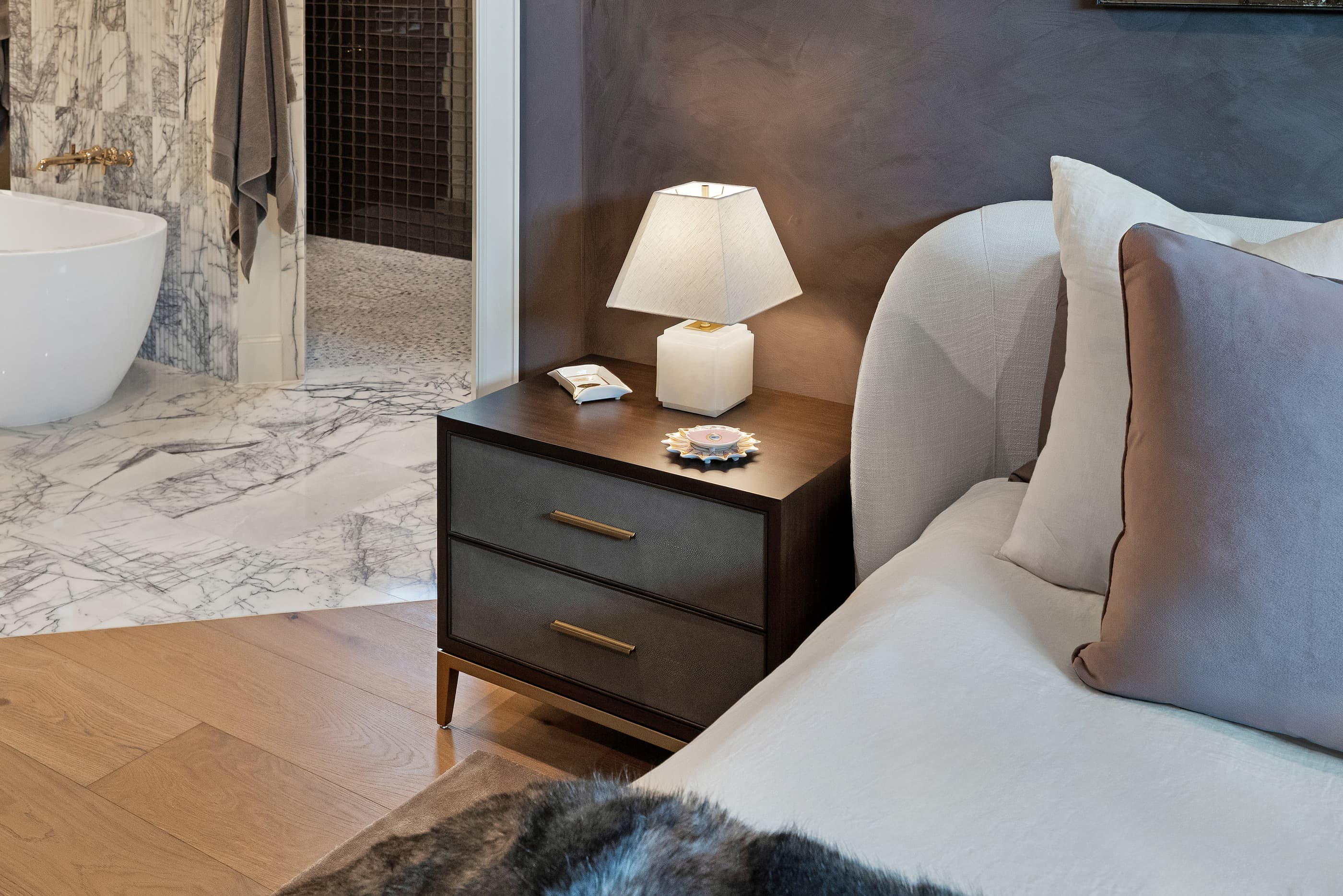 Bedroom view with a nightstand and a freestanding tub in the primary bath beyond