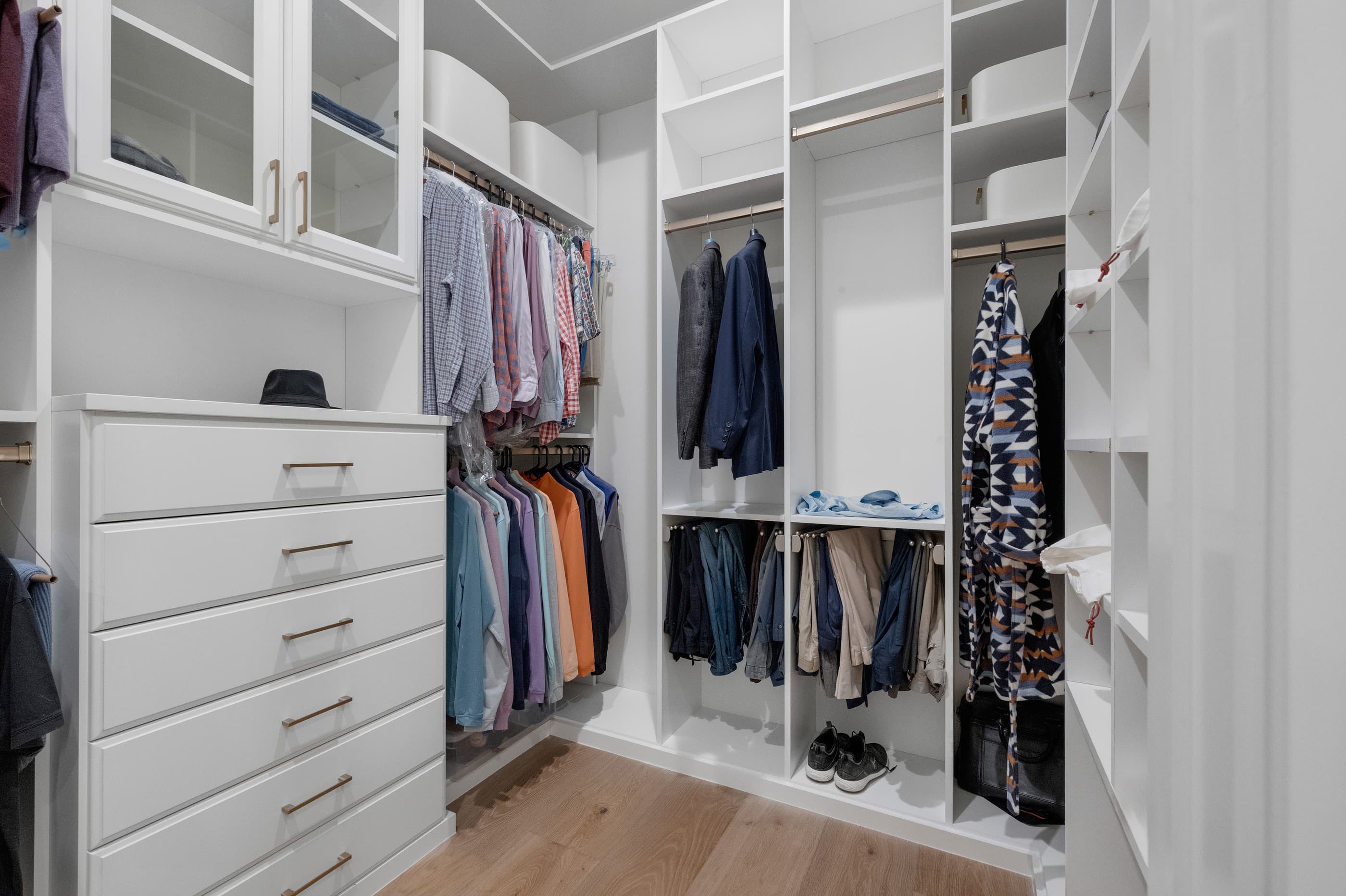 Walk-in closet with white built-in drawers, hanging rods and shelving