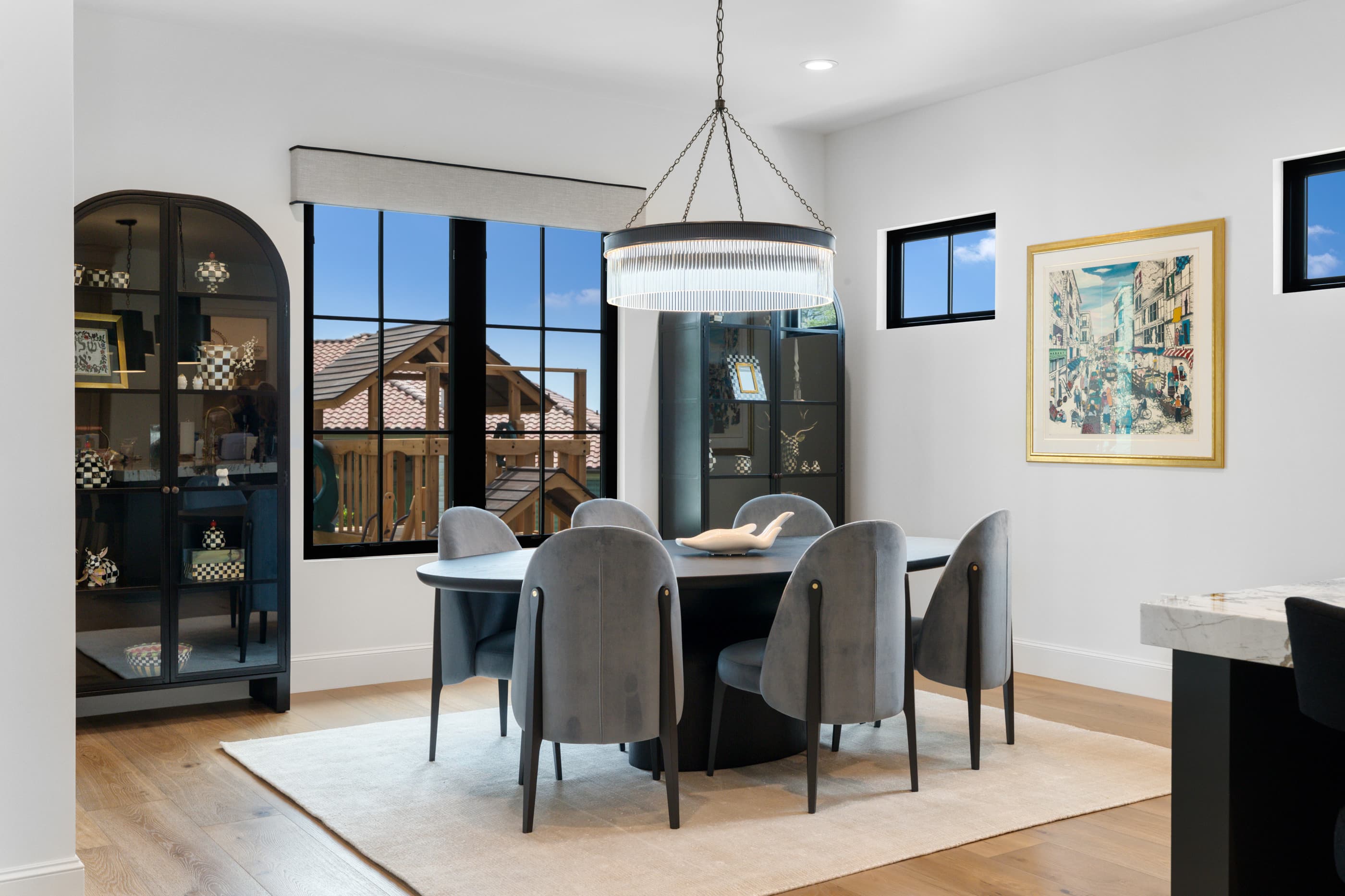 Breakfast dining area with an arched black display cabinet, chandelier and round table with gray chairs