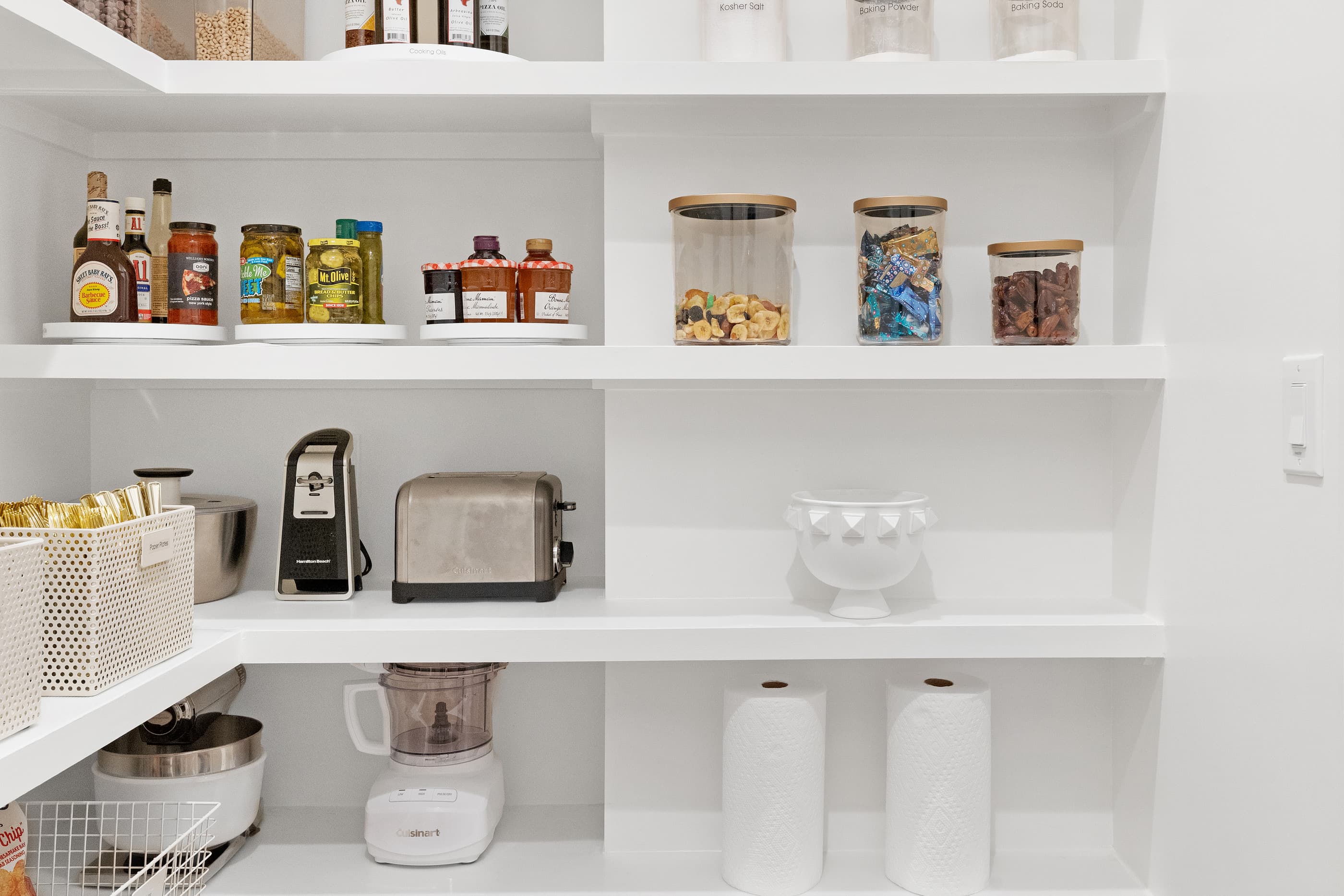 Walk-in pantry with white shelving, glass storage jars and small appliances