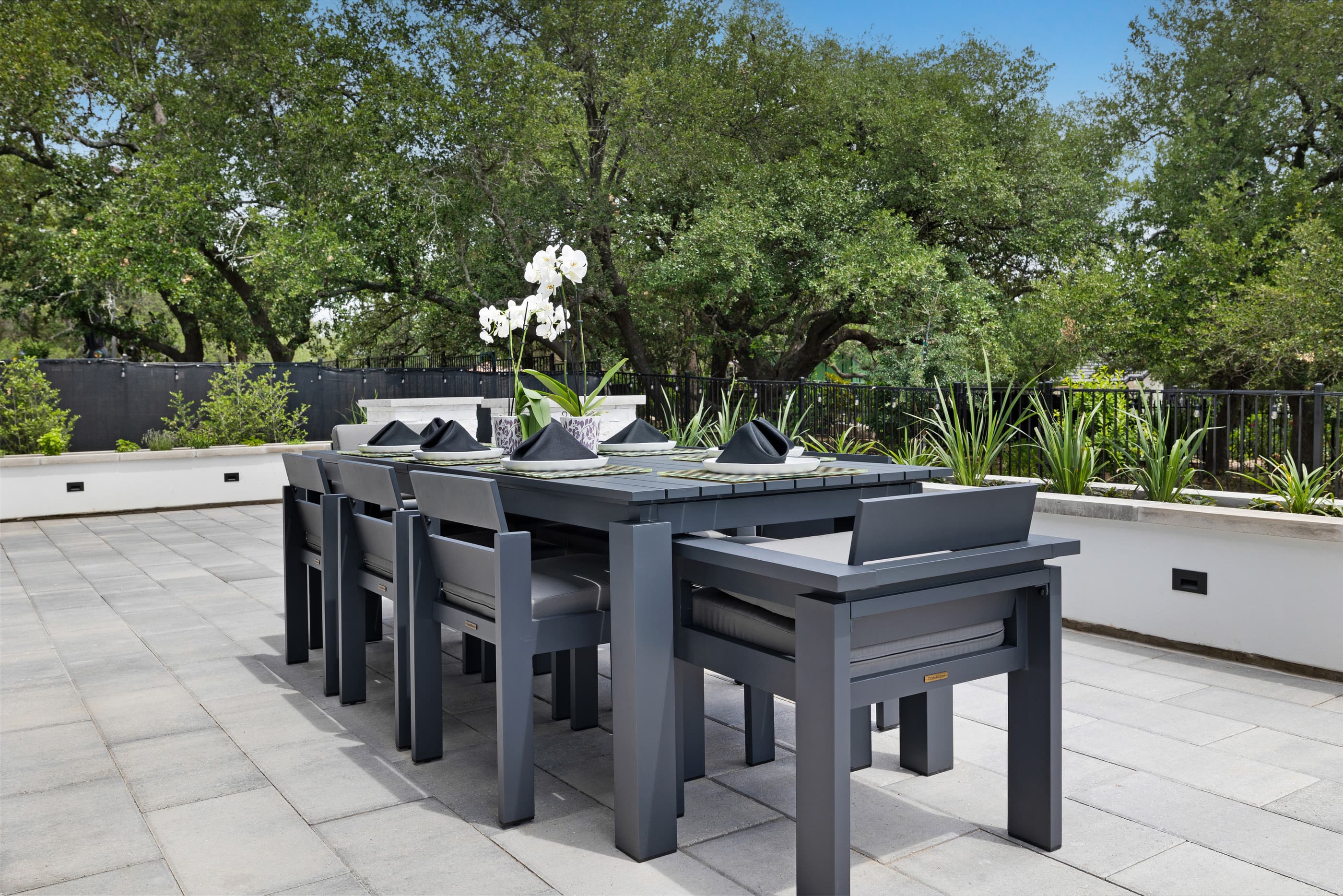 Paver patio with a long outdoor dining table and raised planter walls