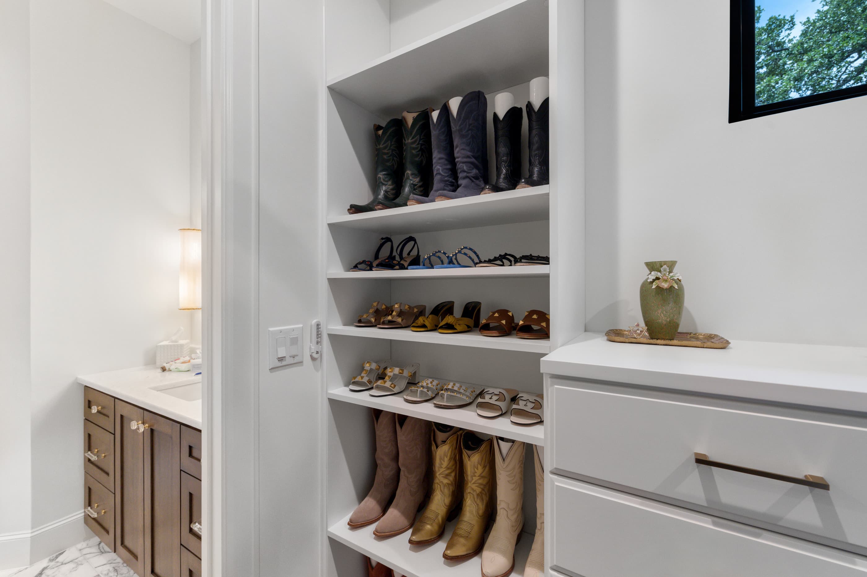 Dressing area with built-in boot and shoe shelving beside a vanity and window