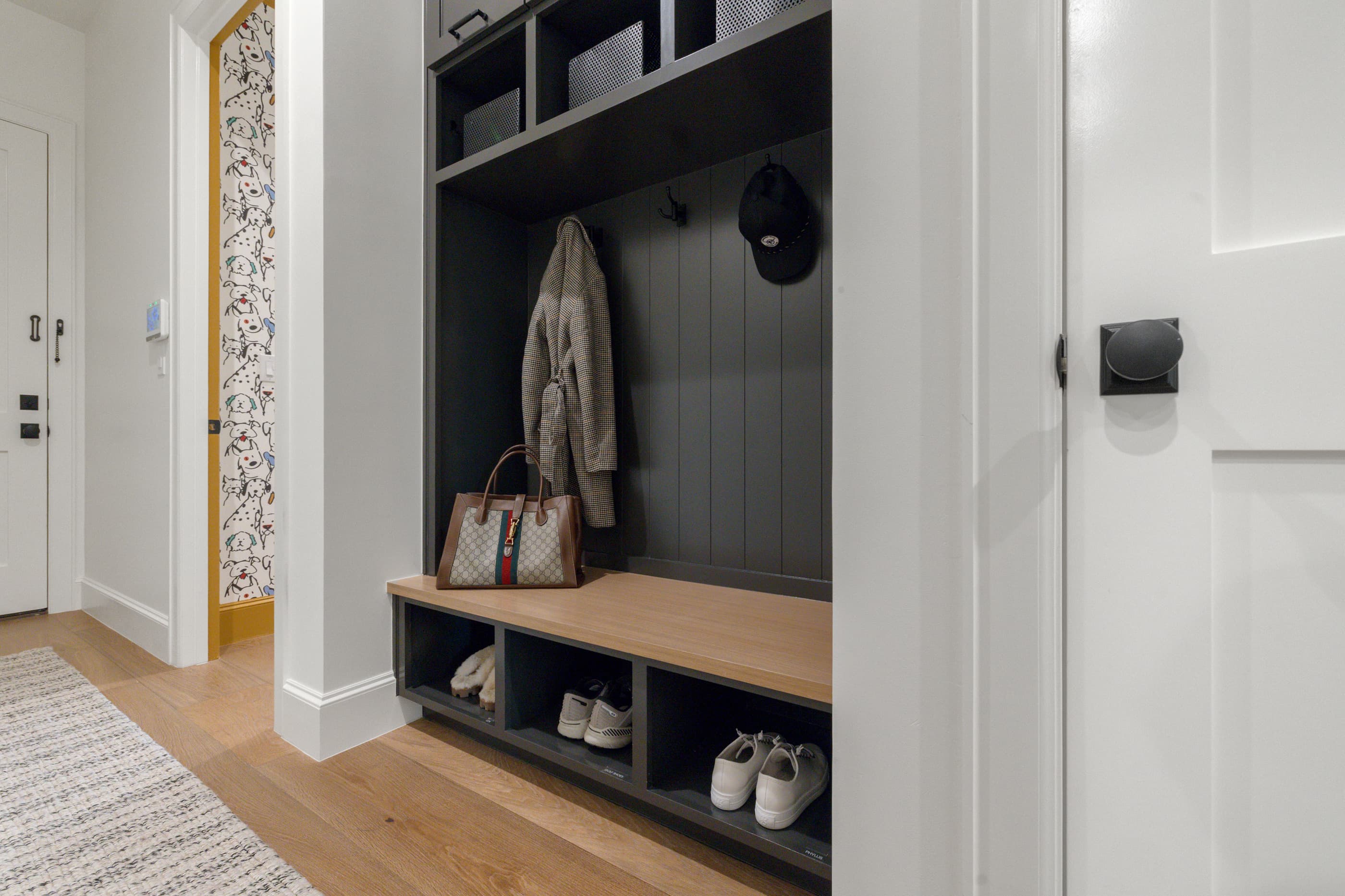 Mudroom with a built-in bench, cubbies, coat hooks and a dark paneled back wall