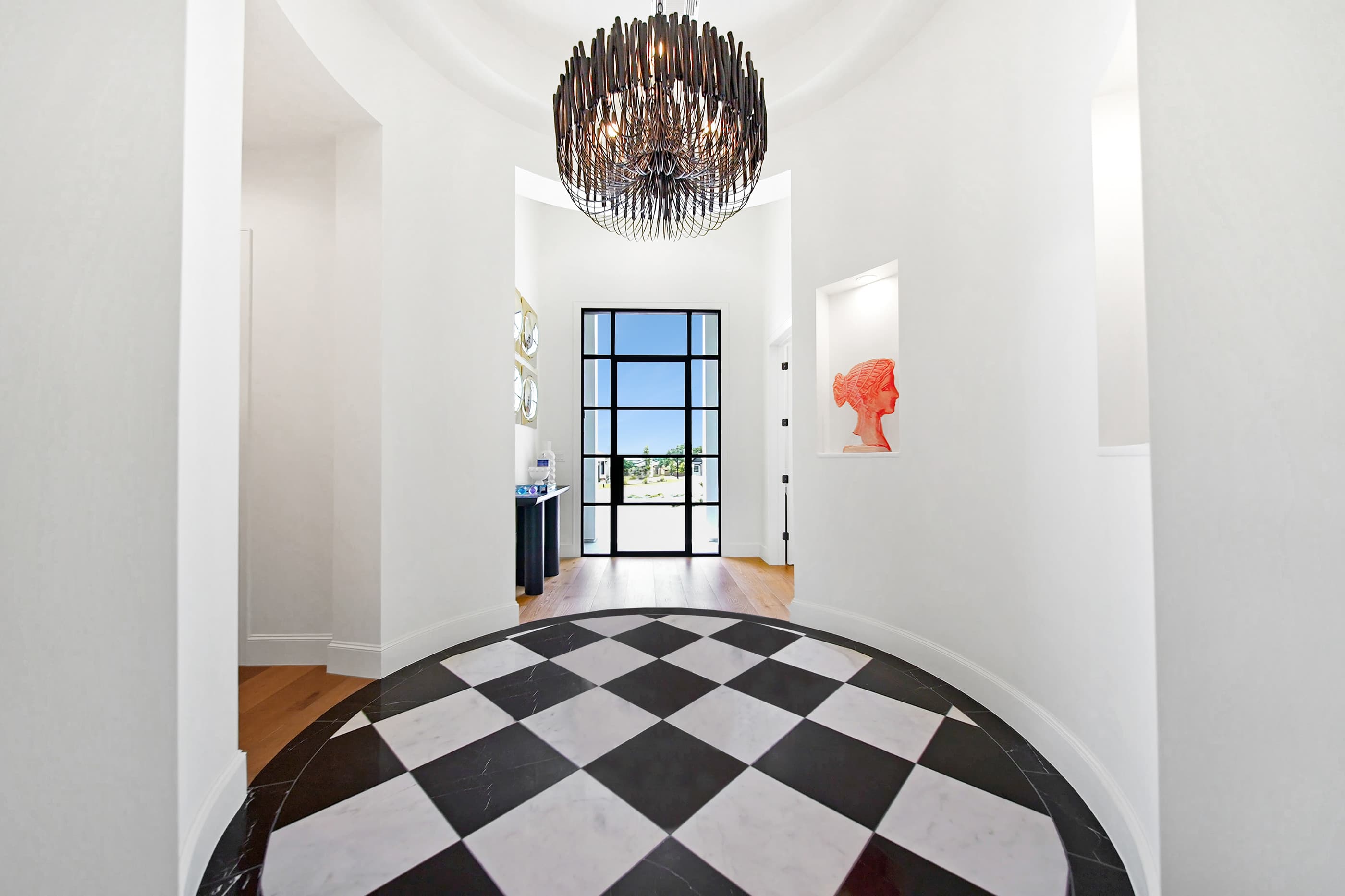 Entry foyer with a round checkerboard floor inlay, a drum chandelier and a steel-framed front door