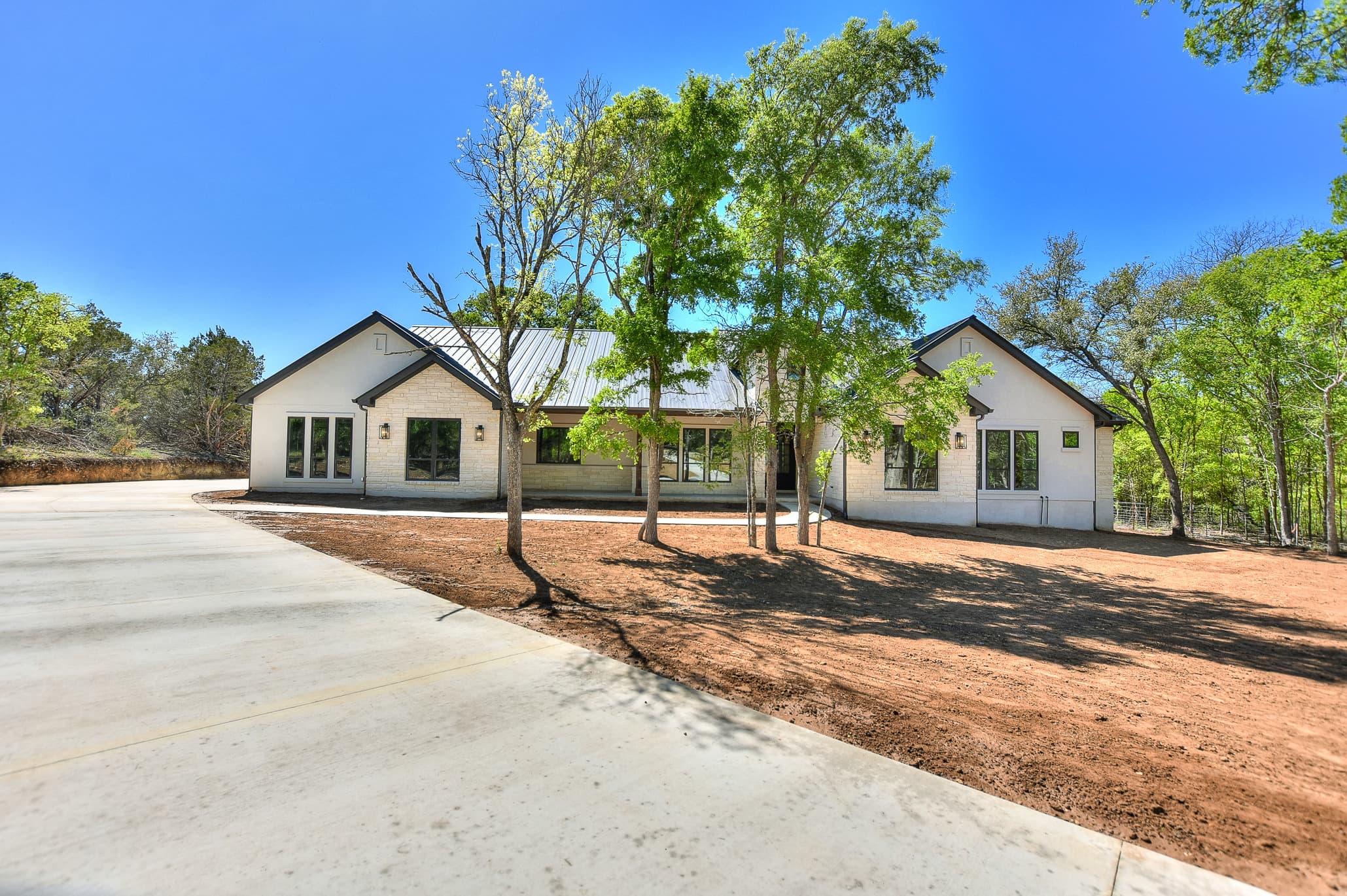 Custom home exterior beneath Hill Country oaks